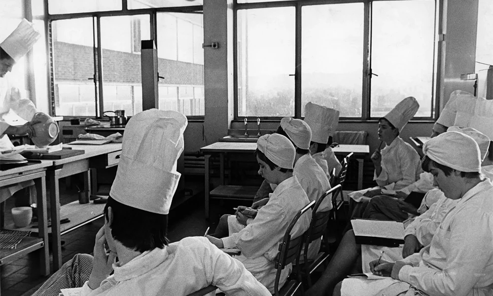 A black and white photo with the people with chef hats on